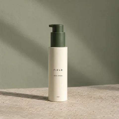 FIELD daily lotion with a green pump on pale limestone